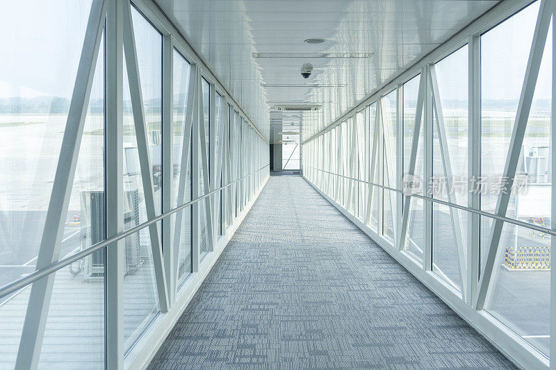 Passenger boarding bridge leading to the plane in the airport